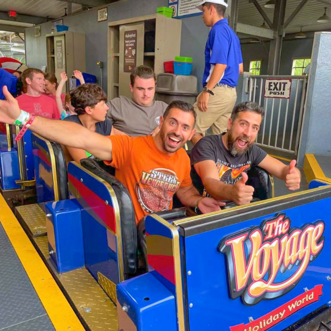 Two people give a thumbs up in the front row of The Voyage train in the station.