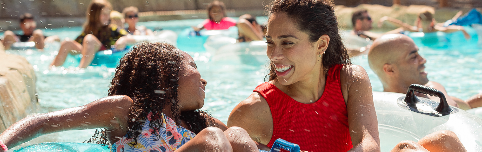 A mother and daughter float in Bahari River and smile at one another as other families float around them.