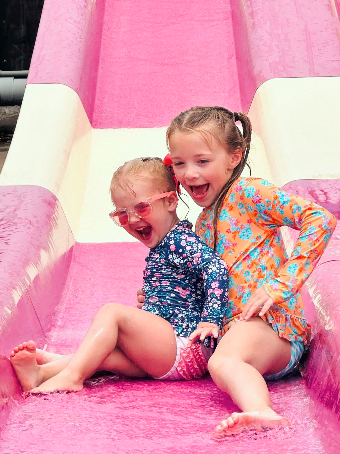 Two children slide down a children's water slide