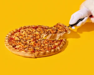 Santa's hand pulling a slice from a whole sausage pizza at Holiday World & Splashin' Safari in Santa Claus, Indiana.