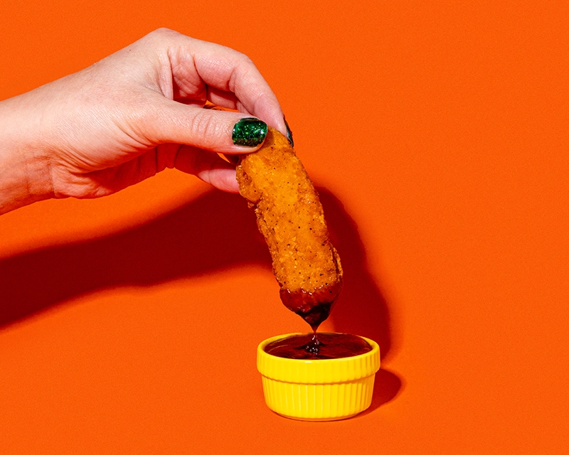 A chicken tender being dipped into barbecue sauce at Holiday World & Splashin' Safari in Santa Claus, Indiana.
