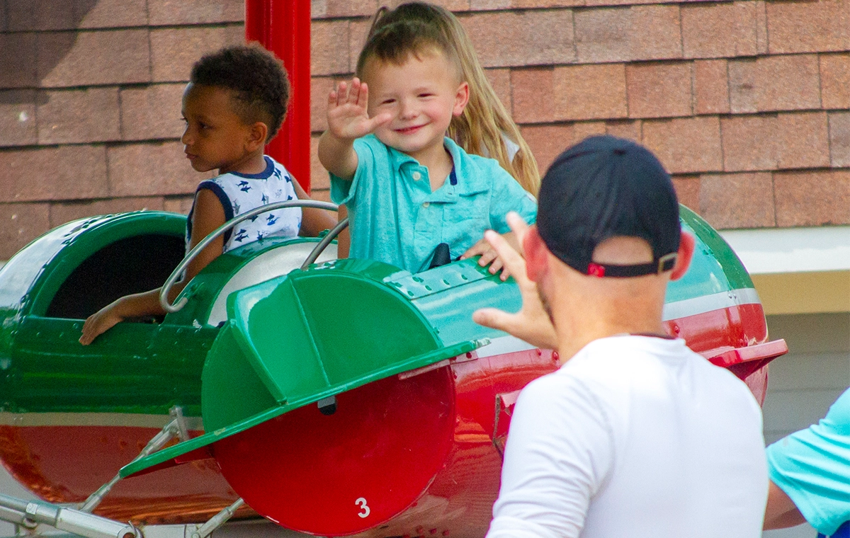 A small boy waving to his father while riding Comet's Rockets at Holiday World & Splashin' Safari in Santa Claus, Indiana.