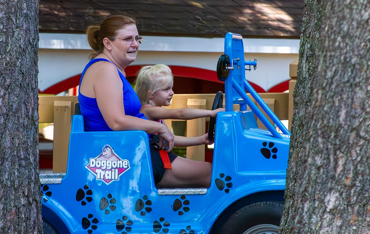 Looking through the trees at a grandmother and grand daughter riding Doggone Trail at Holiday World & Splashin' Safari in Santa Claus, Indiana.