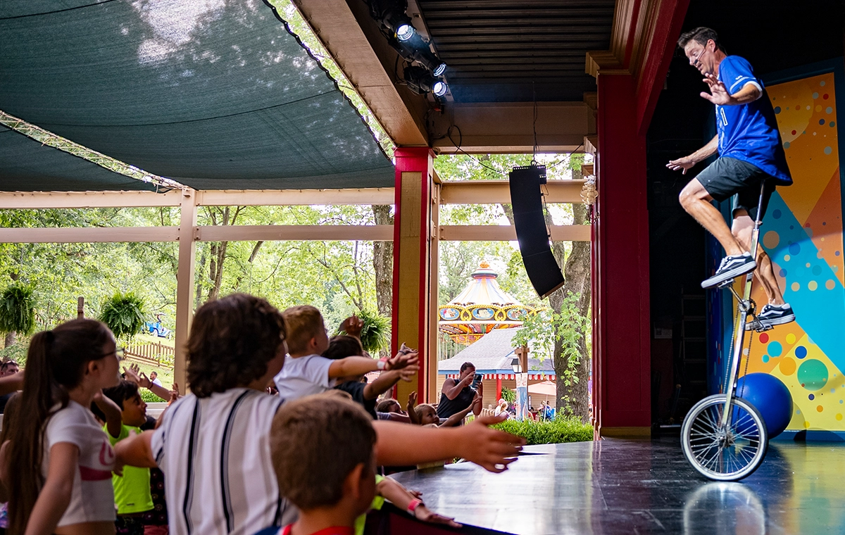 Matt Jergens riding a unicycle during the Out of Hand Comedy Juggling Show at Holiday World.