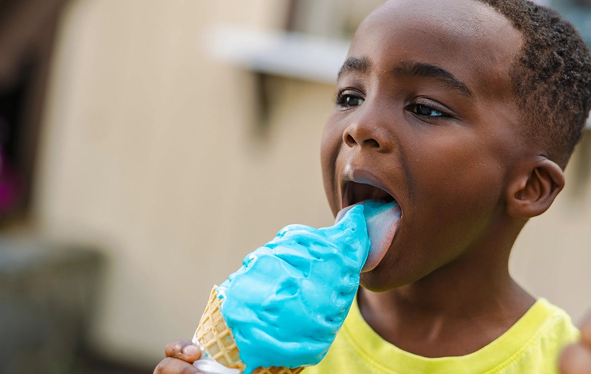 A young boy licks a tall "blue ice cream" from Udderly Blue.